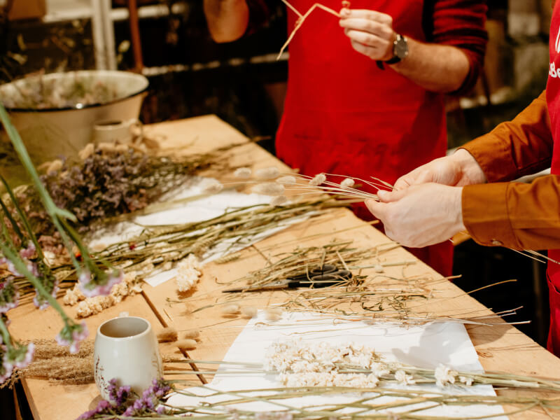 Close up of colleagues making dried floral arrangements together