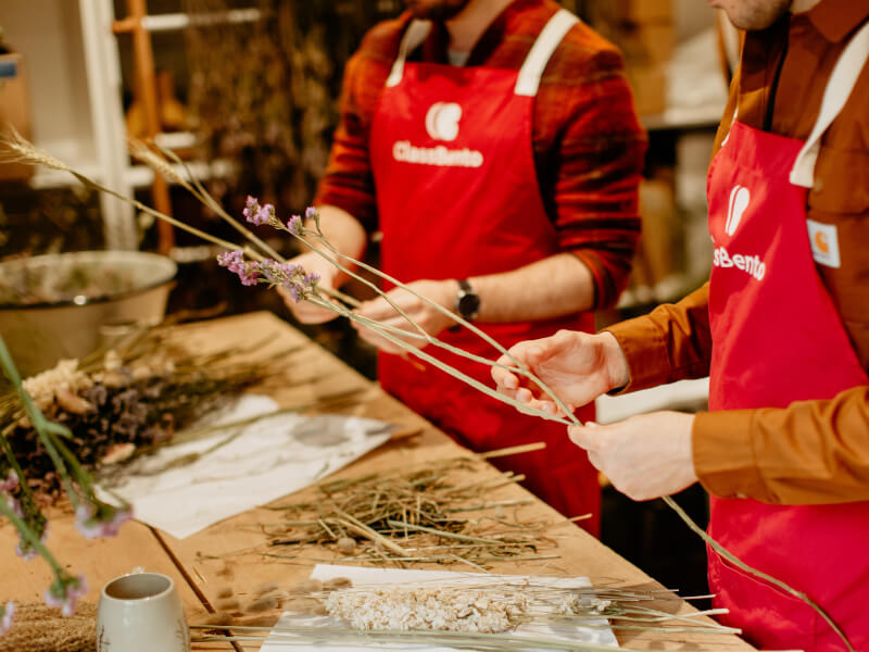 Close up of two people standing side by side at a dried flower arranging class