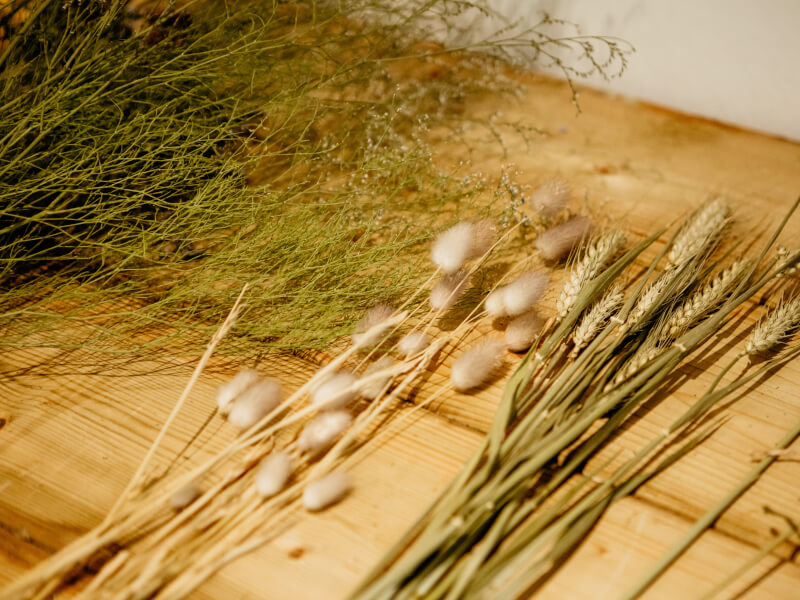 Bunches of dried wheat and grasses lying on a wooden table