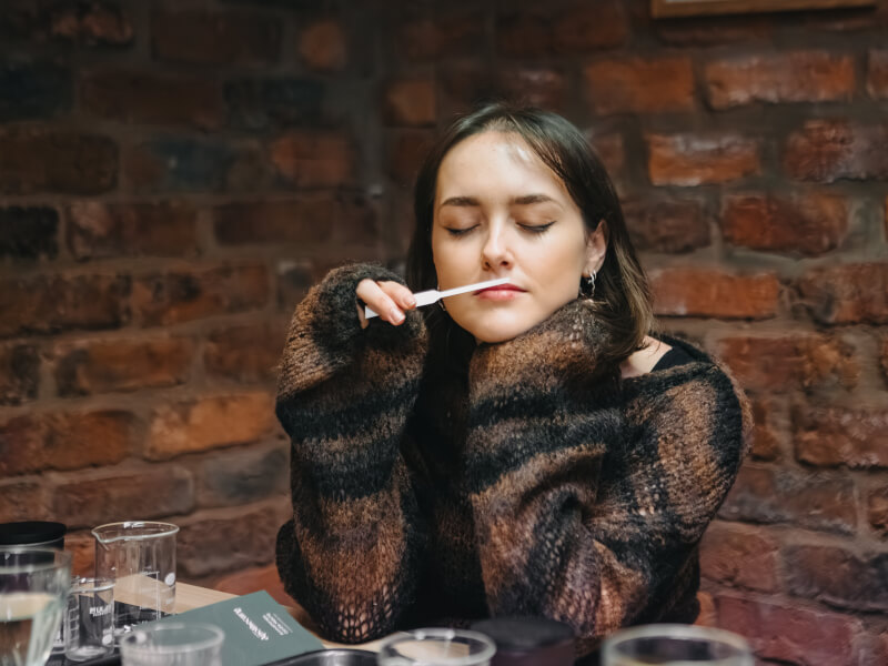 A young woman is smelling essential oil on a paper stick
