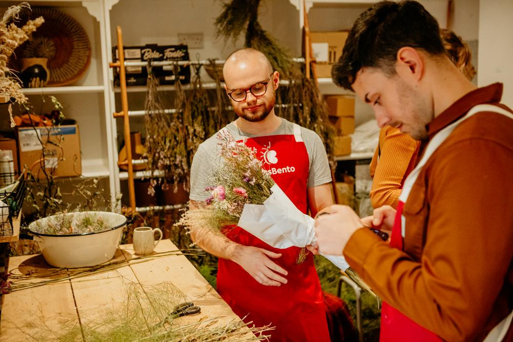 Two men making a dried flower bouquet together