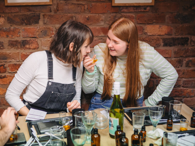 Two women in a candle making class smelling scents