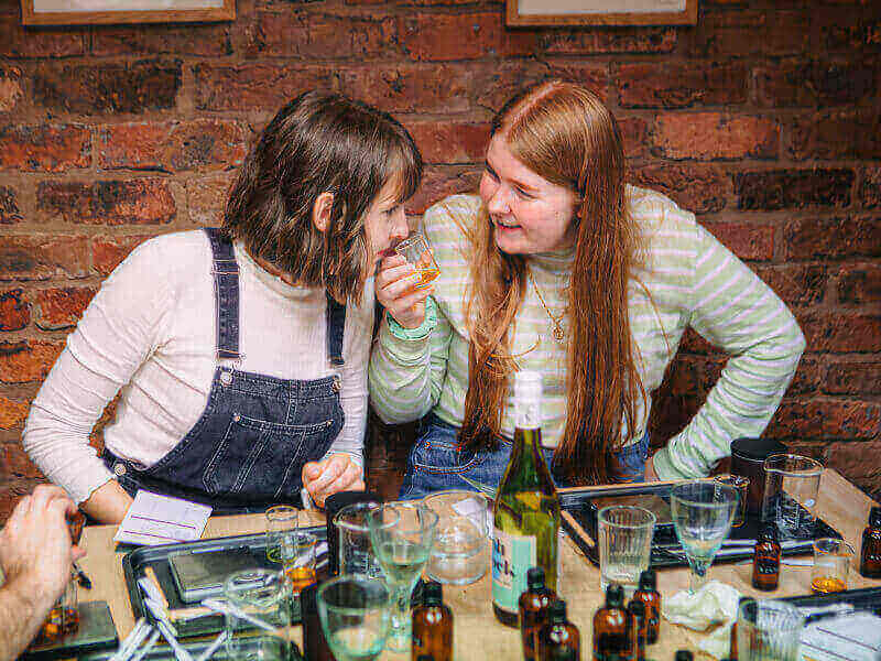 Two women smelling essential oils in a perfume making class
