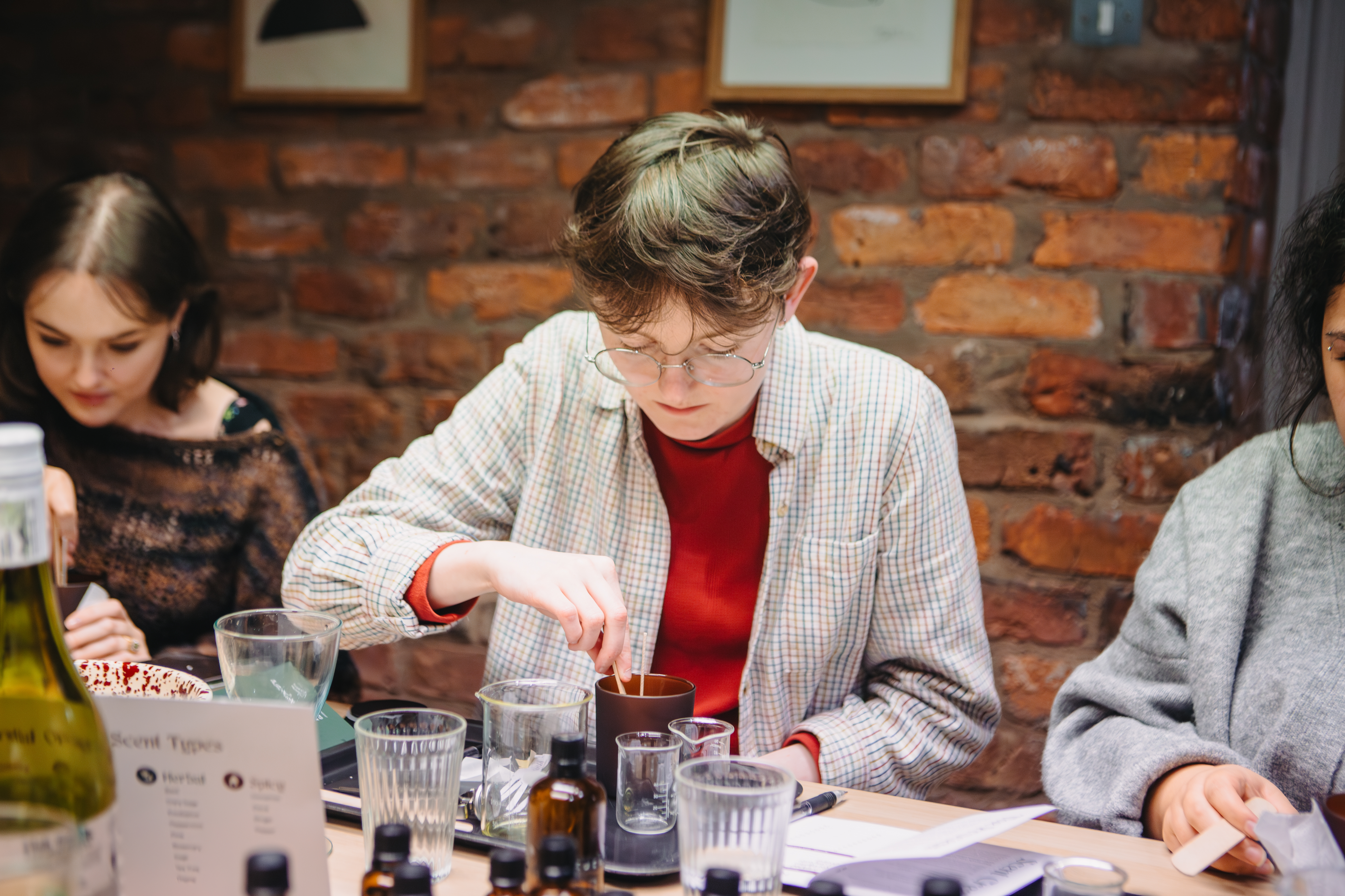 A person adding wax to a brown jar to make a candle