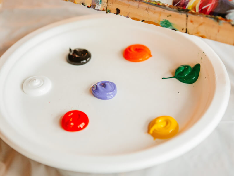 A palette with different blobs of coloured paint ready to be use in a painting class.