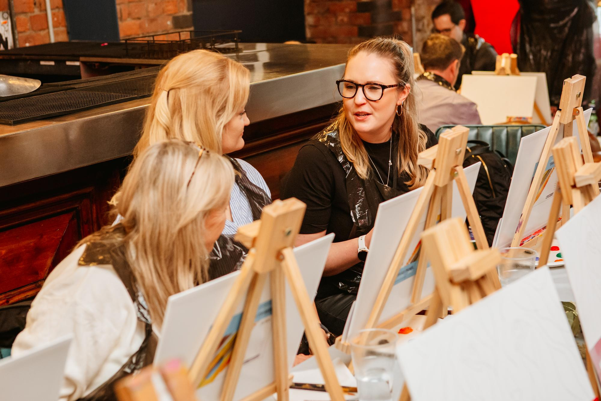 Two women chatting with one another at a paint and sip