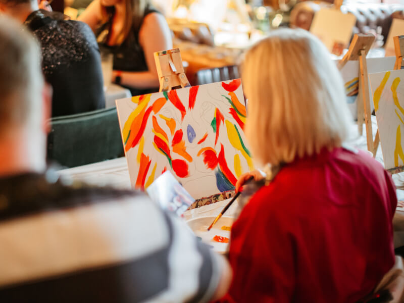 A woman paints a colourful lion in a paint and sip class.