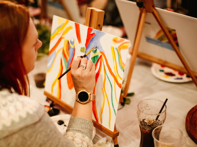Woman painting on a canvas at a paint and sip.
