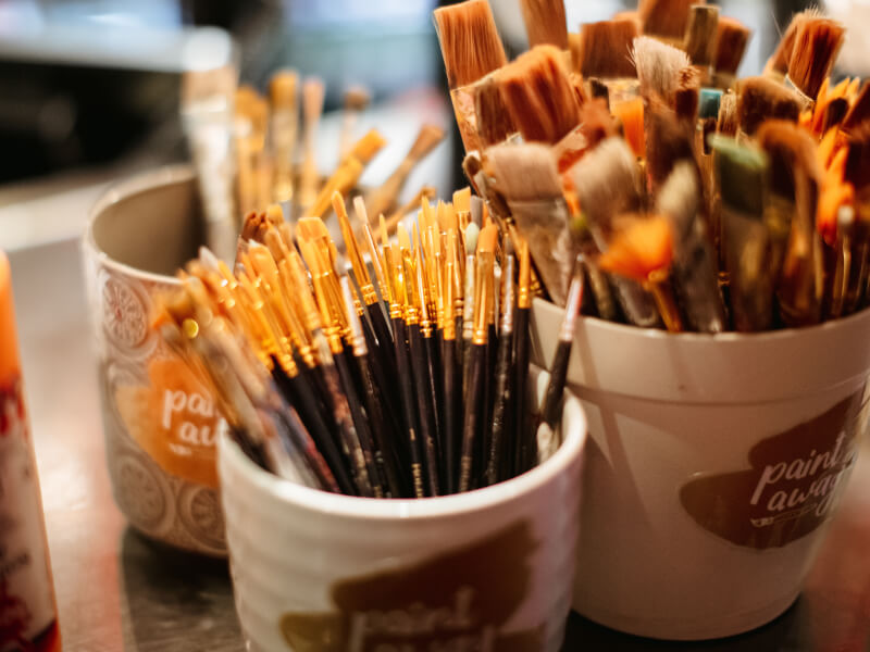 A pot of paintbrushes at a painting class.