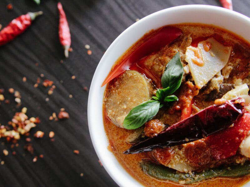 A red curry with vegetables garnished with fresh herbs