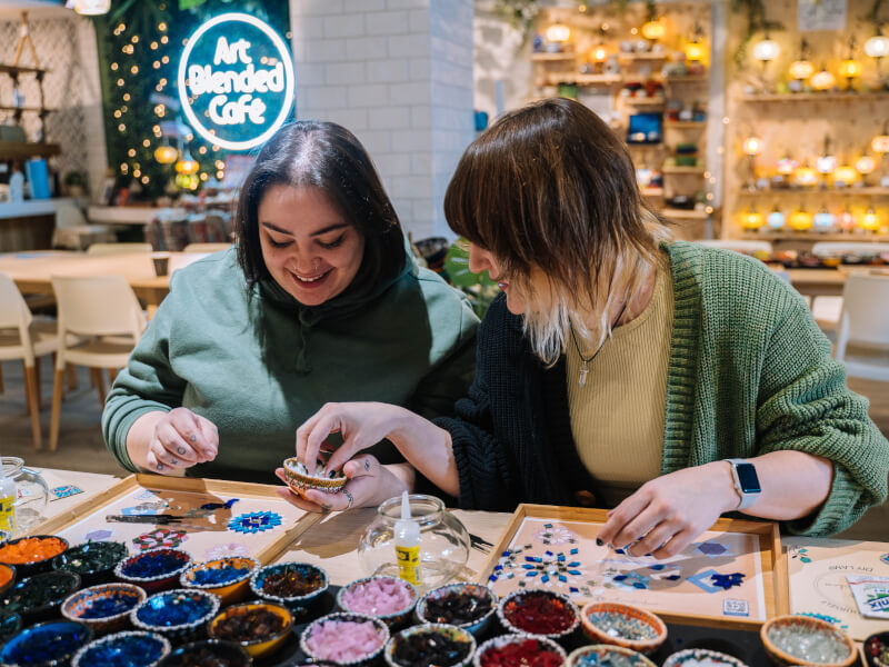 Two people creating mosaics together