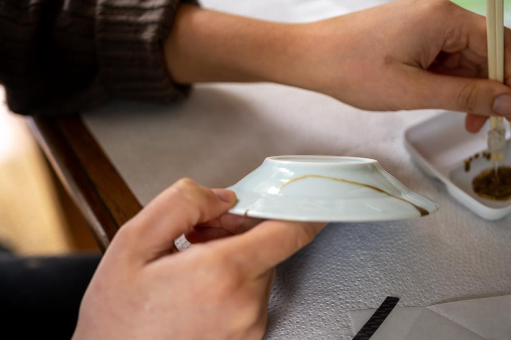 Person preparing a small ceramic plate at a kintsugi class