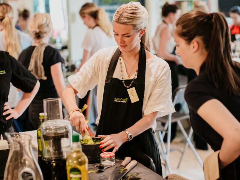 Two women make pesto in a cooking workshop