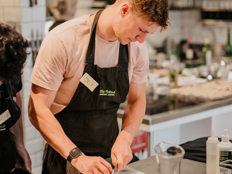 A man slices an onion in a cooking school kitchen.