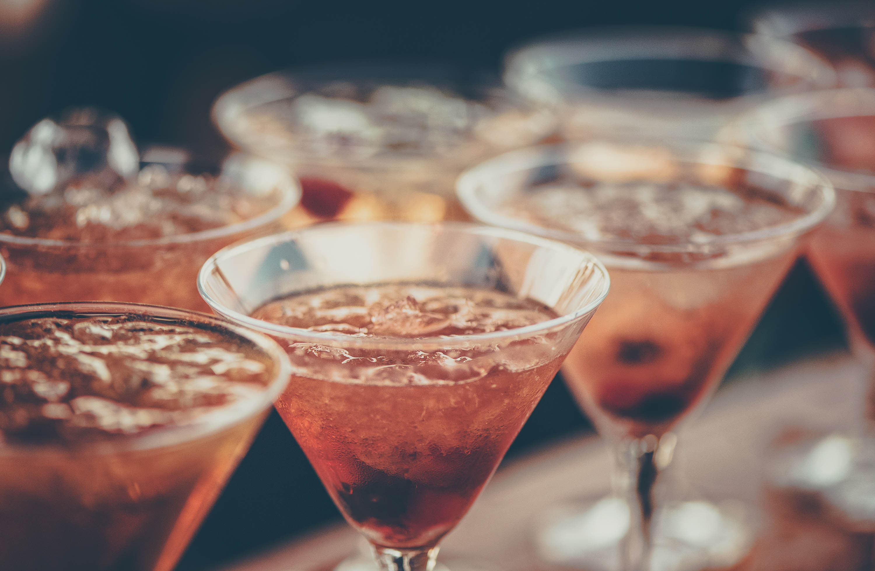 Several delicious cocktails in cocktail glasses filled with ice