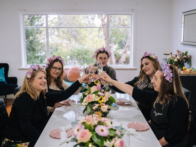A group of women wearing flower crowns toasting with sparkling wine