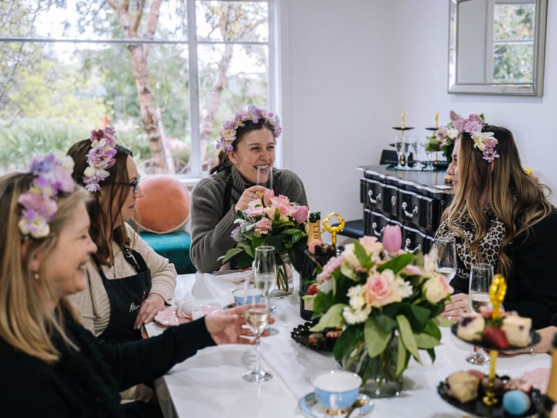 A group of women smiling and laughing wearing flower crowns