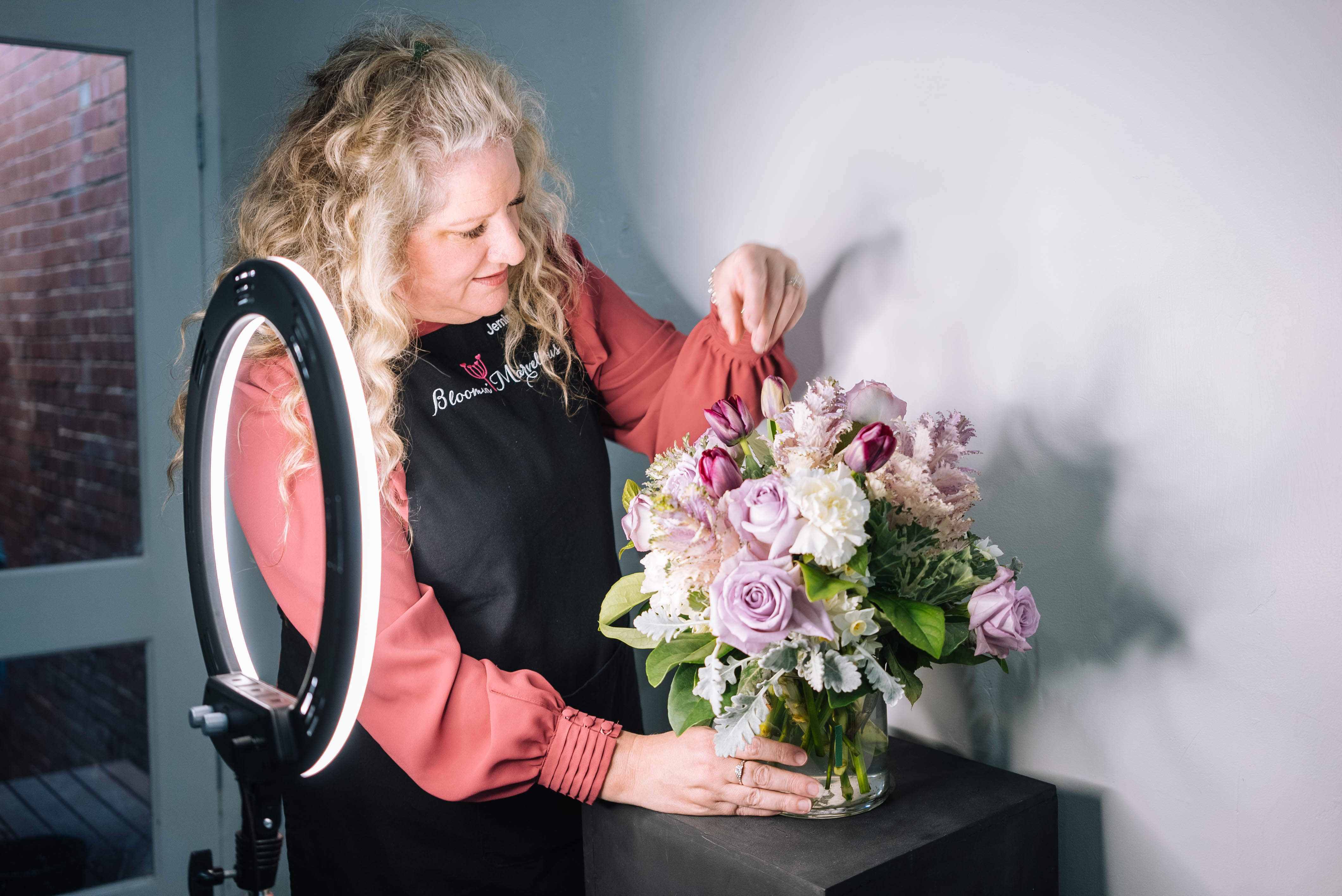 A person taking a picture of a bouquet of flowers using a ring light