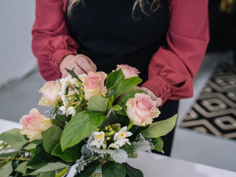 A lady makes a floral arrangement out of pink roses.