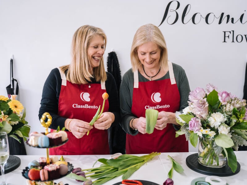 A mother and daughter smile and laugh at a flower arranging class