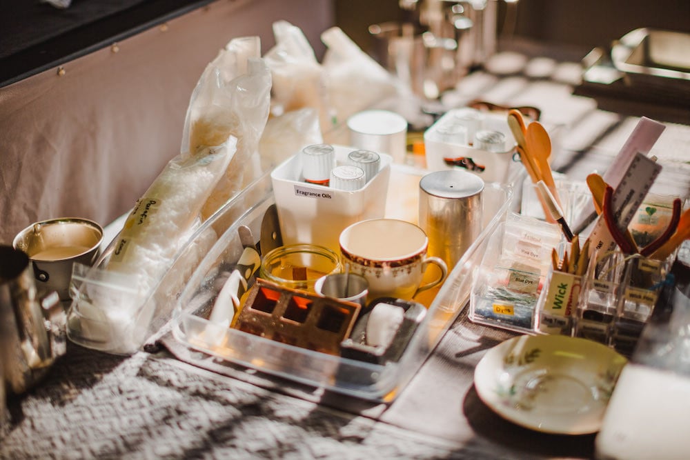 A selection of candle making equipment and materials displayed on a table