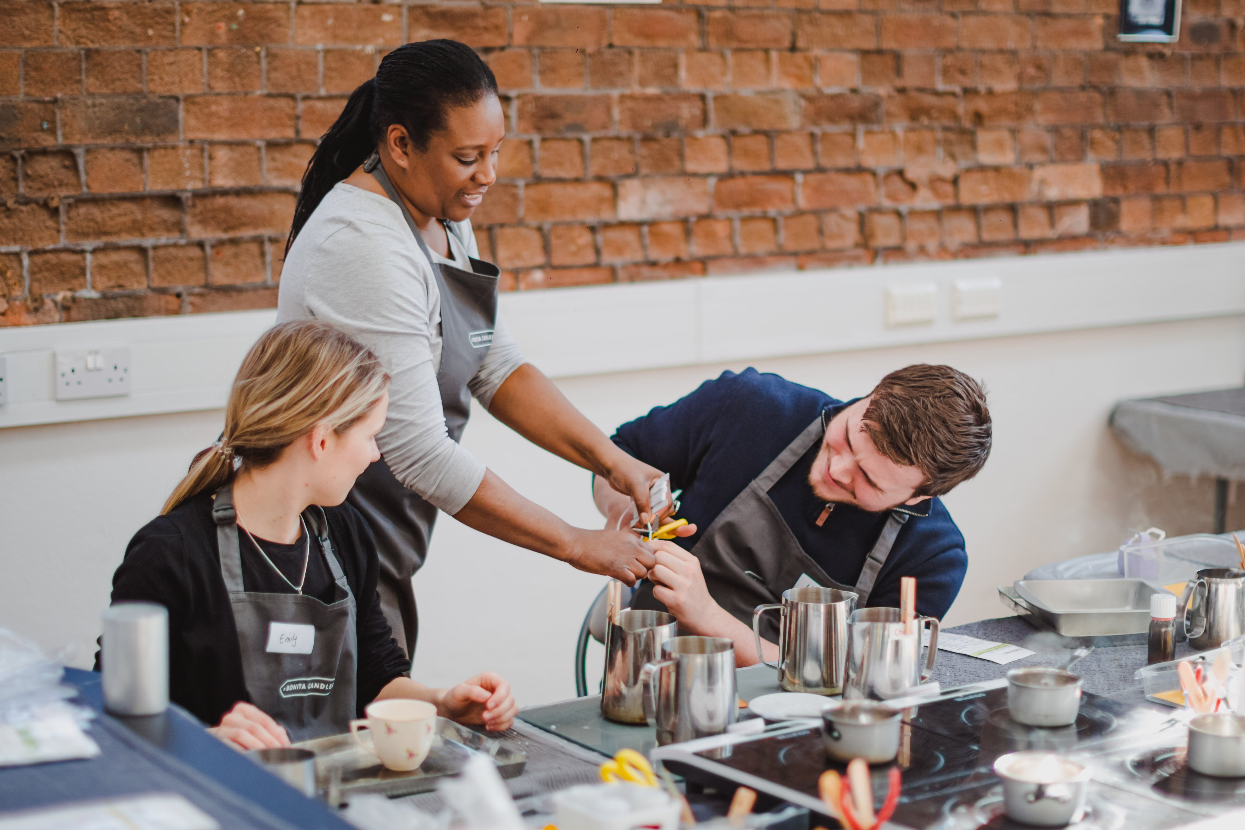 A couple learning from their teacher how to make candles
