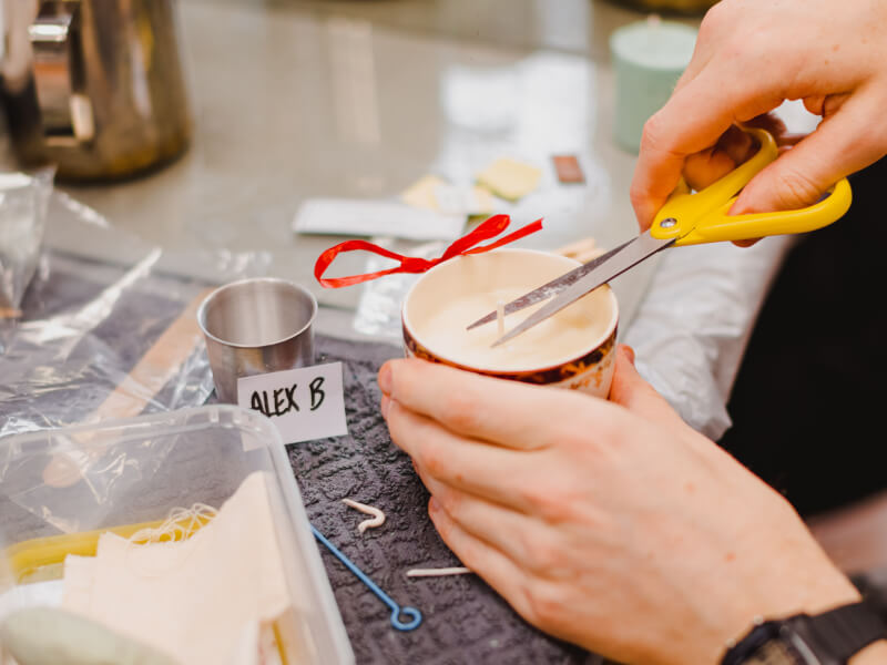 Close up of someone trimming a candle wick with scissors