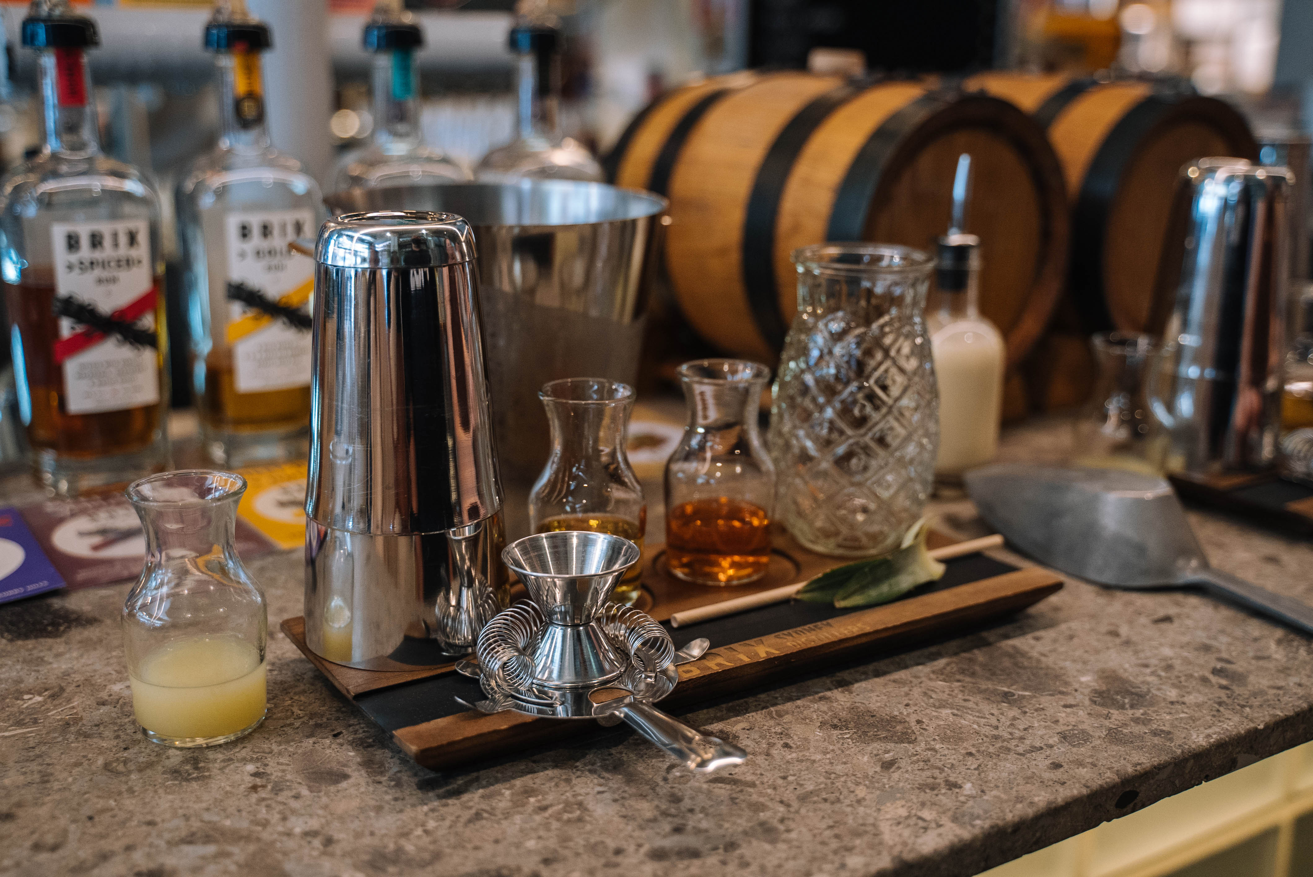 An array of cocktail making tools and ingredients arranged on a marble-top bar