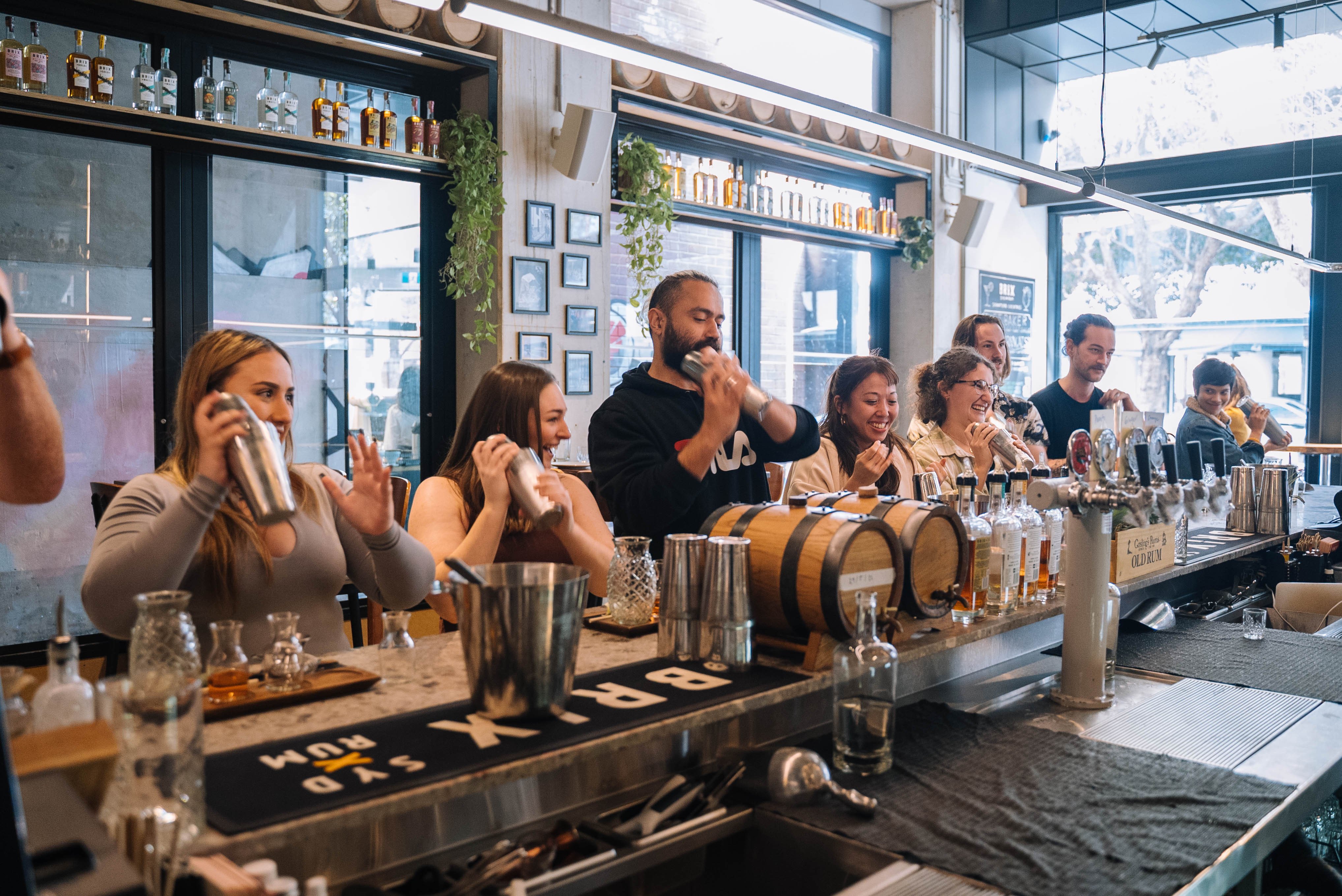 A group of workmates shaking cocktails together at a bar
