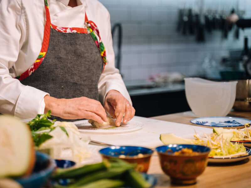 Hands making a summer roll at a cooking class.