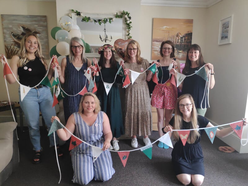 A group of people have made bunting and are holding it up for a photo