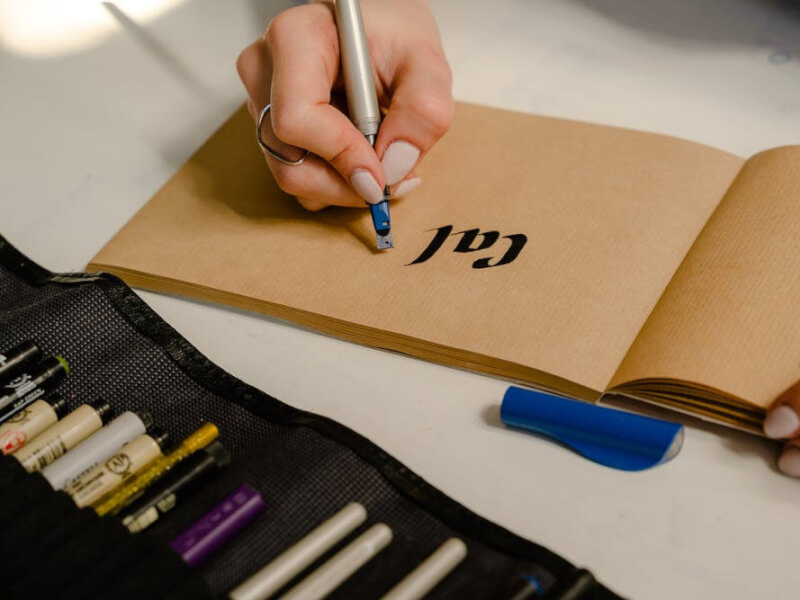 A woman writing in lettering calligraphy on paper.