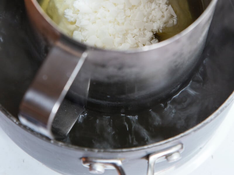 White wax that is starting to melt in a metal jug over some heat.