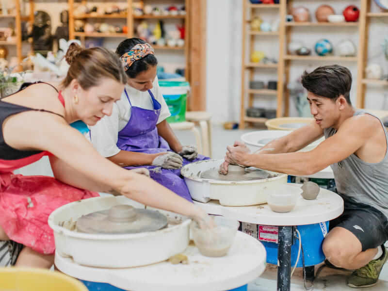 People making pottery at a wheel throwing class. 