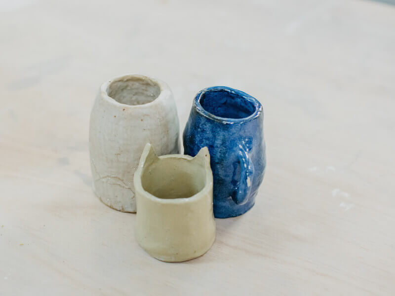 Three handmade pots at a pottery class.