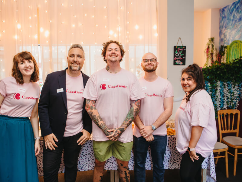 Five smiling adults wearing ClassBento tshirts pose for a photo