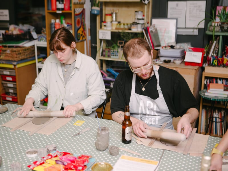 A couple sitting side by side at a hand building pottery class