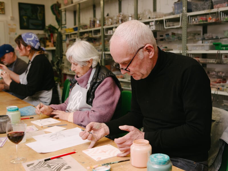 An older couple working at a tile painting workshop
