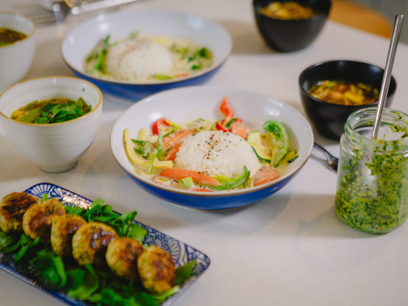 A selection of Thai food sits on blue plates on a table