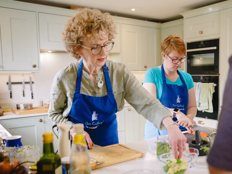 Woman cooking at a cooking class wearing blue apron