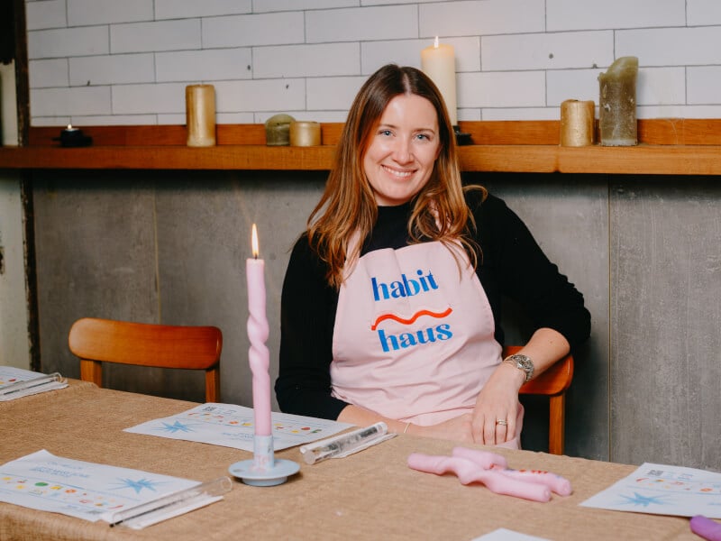 Harri Price of Habit Haus, sits at a table with bendy candles in front of her