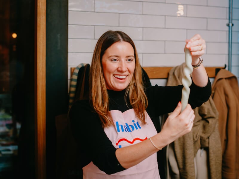 Harri Price stands at the front of a workshop, showing people how to twist a candle