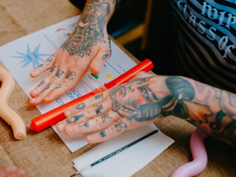 A close up of a person with tattood hands rolling a candle with a rolling pin