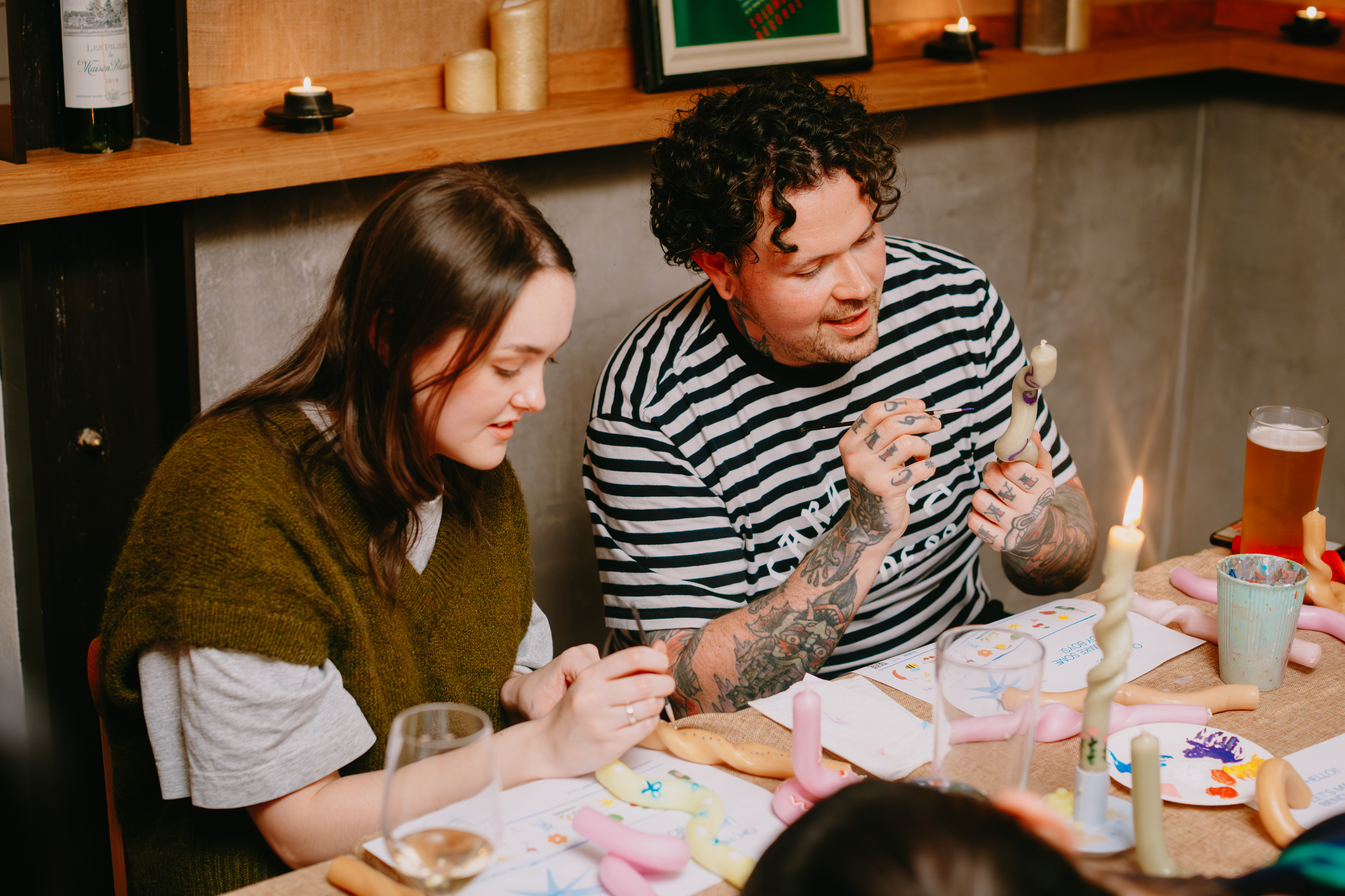 Two people are painting motifs on bendy candles