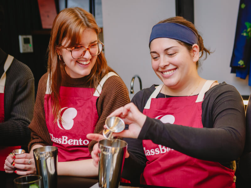 Two women making cocktails and laughing