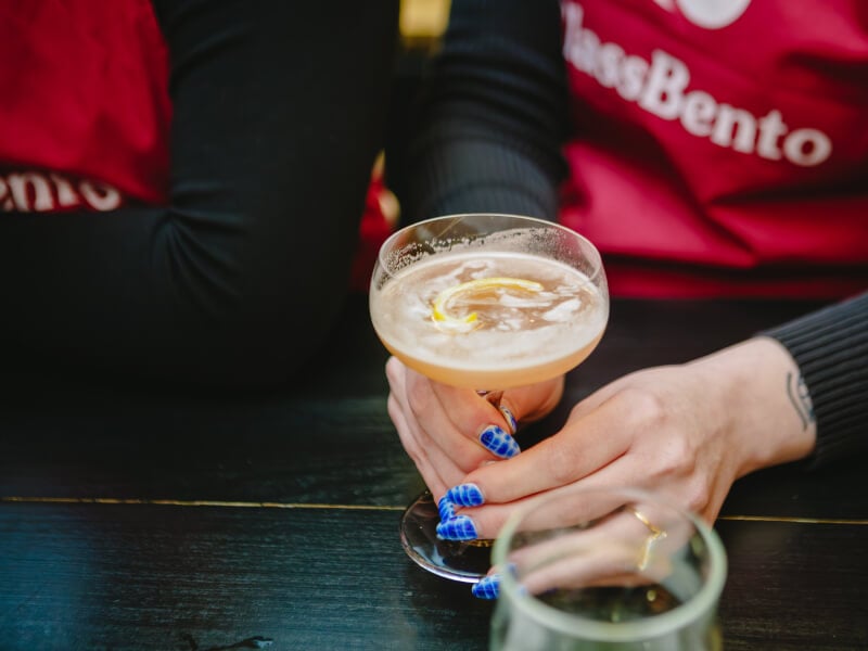 Close up of a person making a pale coloured cocktail in a glass