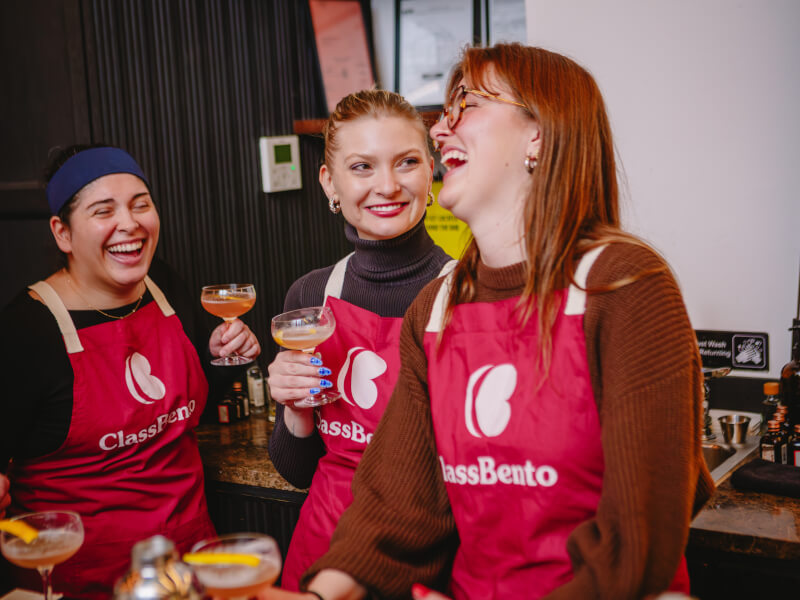 A group of students laughing together at a cocktail making class
