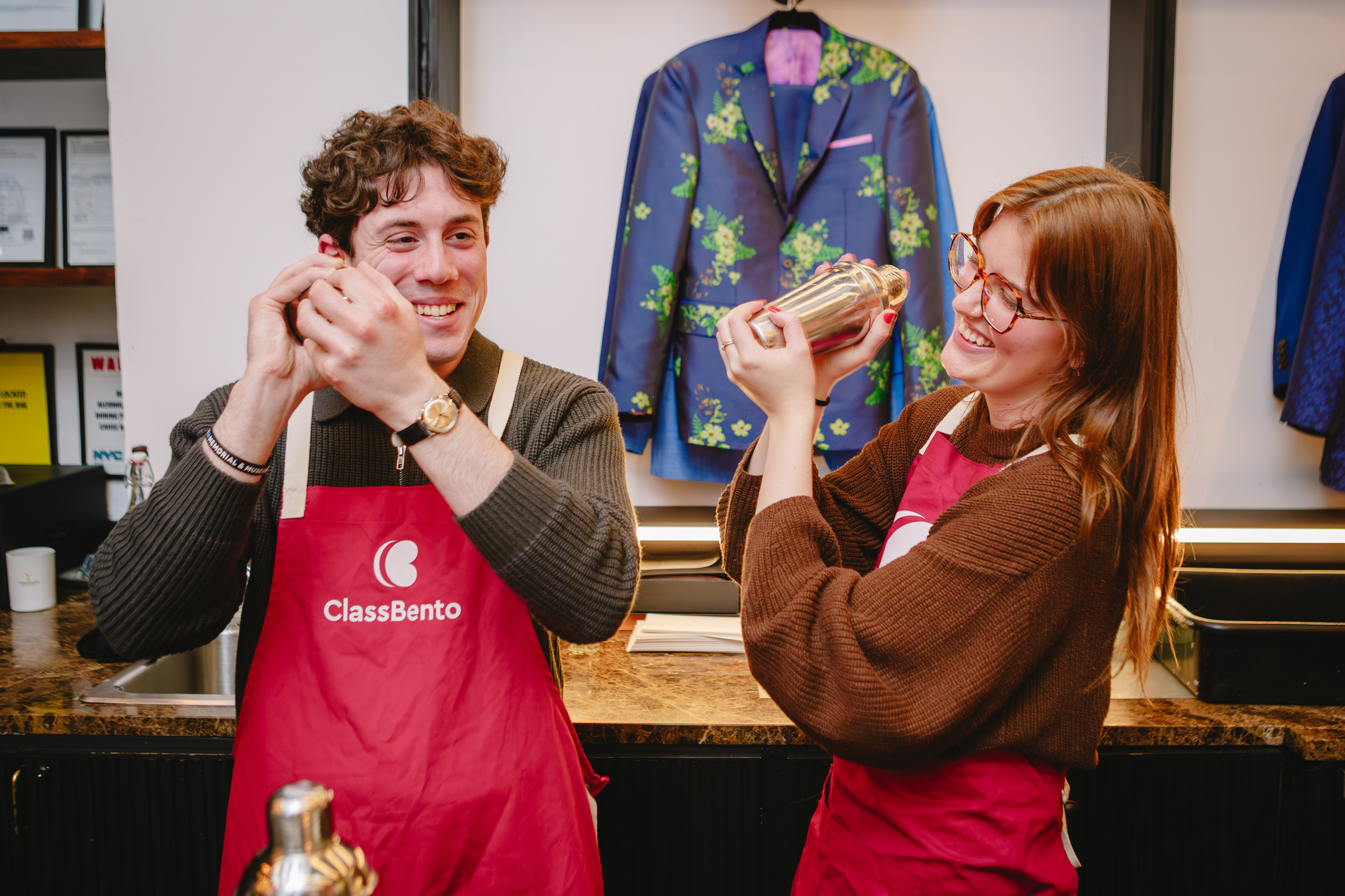 Two people smiling while shaking cocktails together