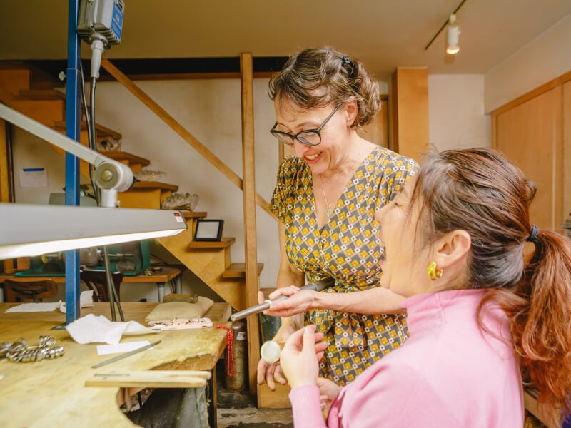 A teacher and student laughing during a jewellery making class