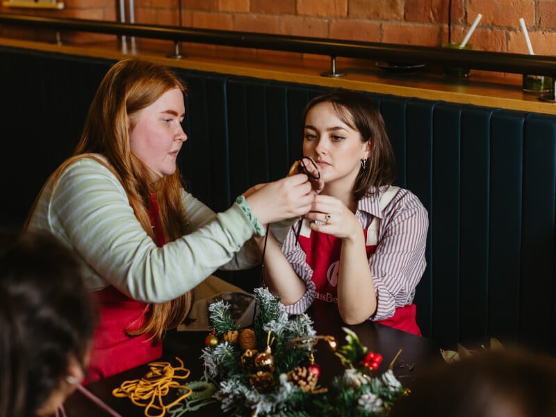 Two women chatting while making Christmas wreaths together